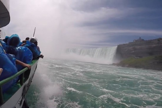 Vista parziale laterale della Maid of The Mist e passeggeri con impermeabile in procinto di avvicinarsi alle Cascate del Niagara