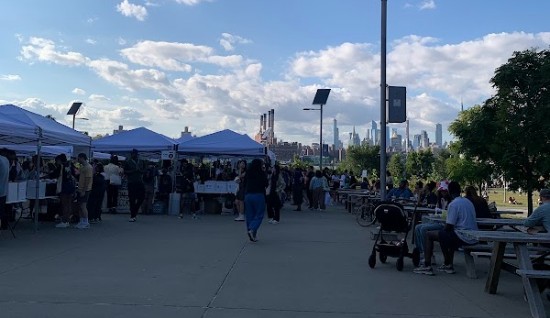 Bancarelle e street food con i grattacieli di Manhattan sullo sfondo a Smorgasburg, Williamsburg